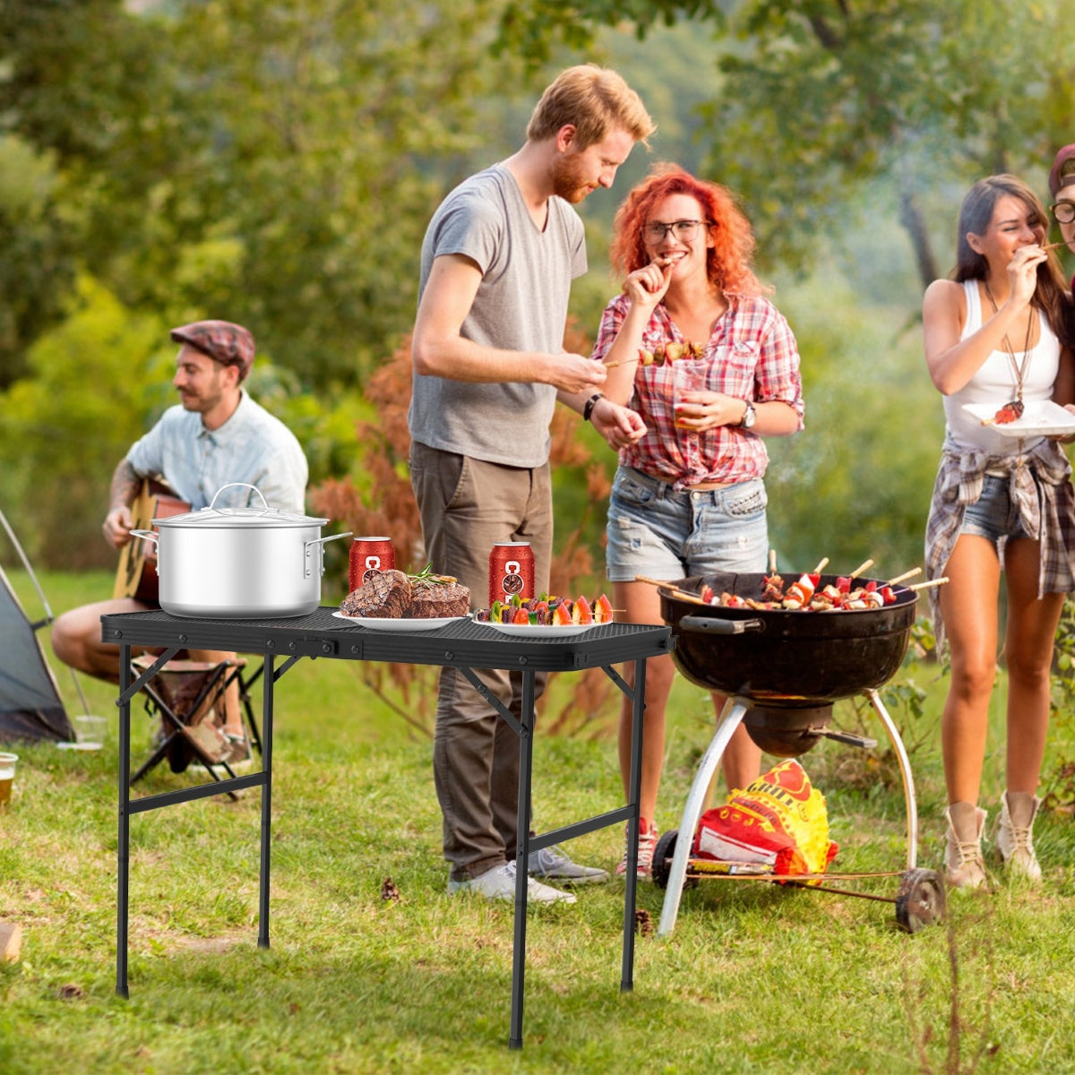 Outdoor folding camping table near grill and group gathering