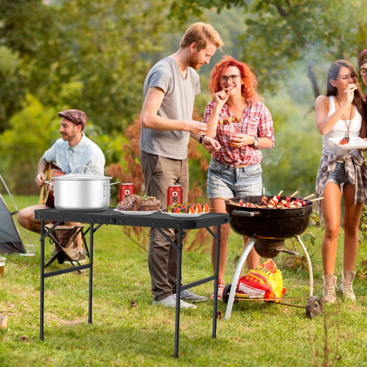Outdoor folding camping table near grill and group gathering