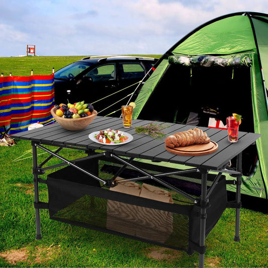 Folding aluminum camping table set beside tent with food and drinks outdoors
