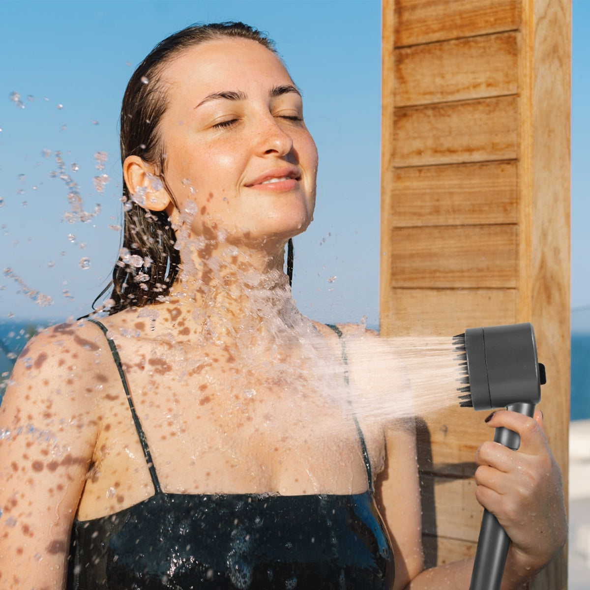 Close view of handheld shower spraying water outdoors